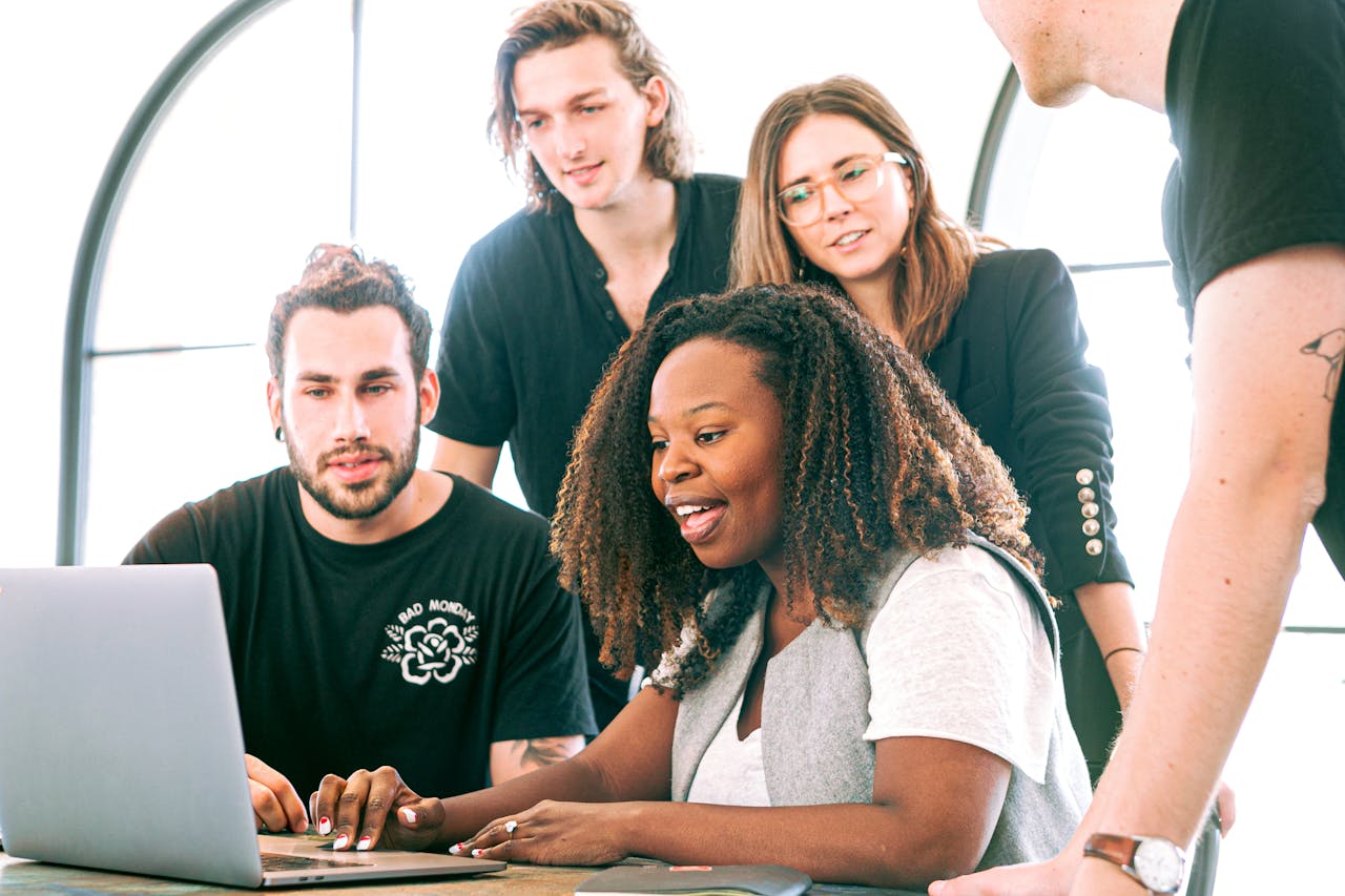 A group of excited people watching a laptop, learning about affiliate marketing tips and exploring powerful affiliate marketing tools for success.