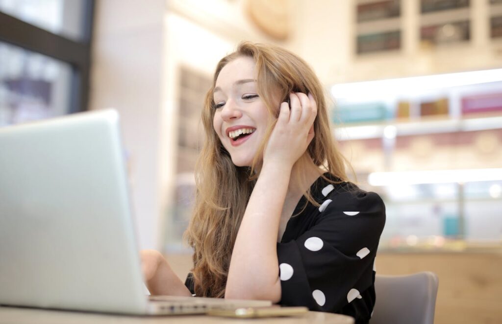  A cheerful woman engaged with her laptop in a cozy indoor setting, learning how to build passive income through live trainings for affiliate marketing.