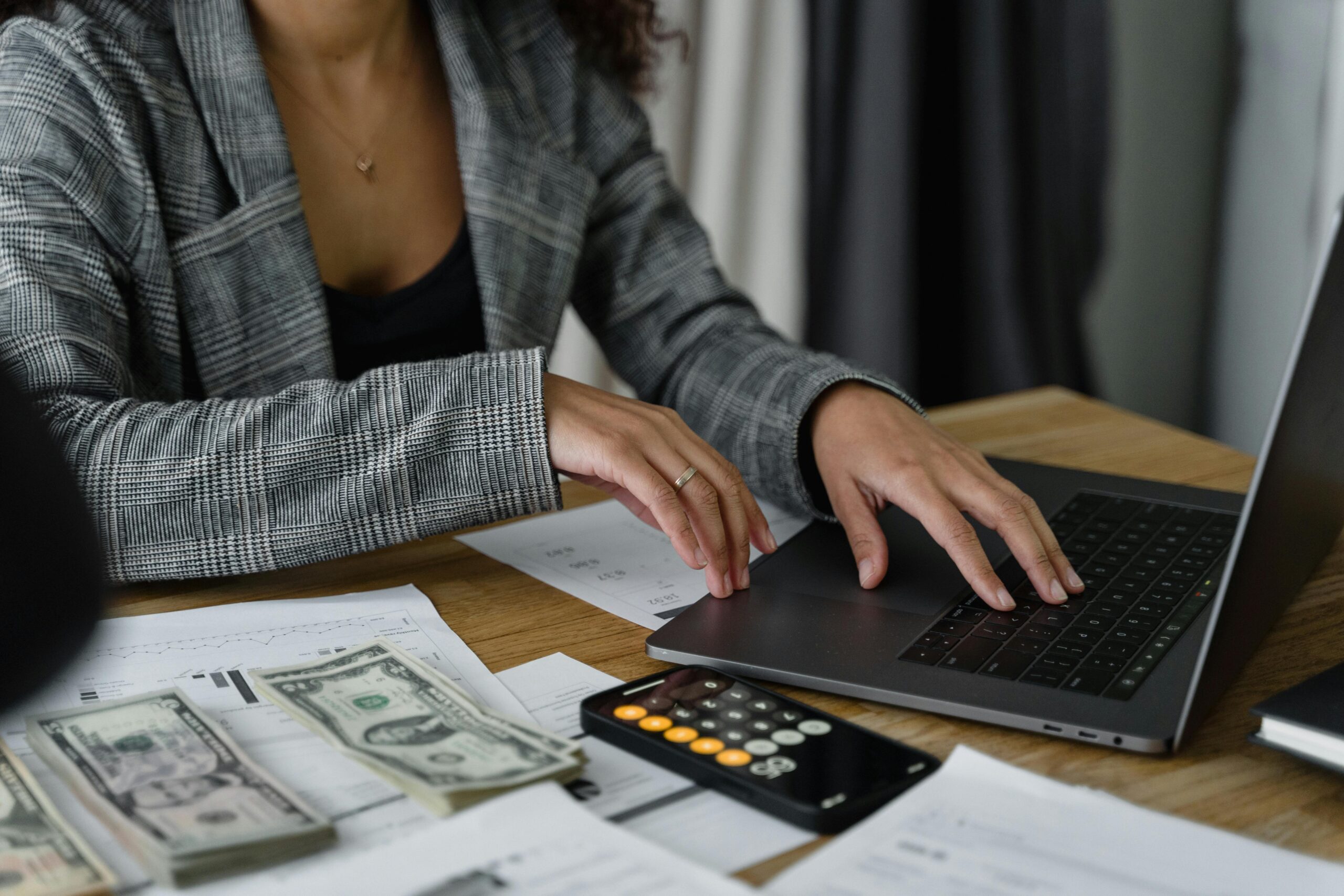 Woman with laptop and dollars, recommended by Filip to start learning affiliate marketing for online income.